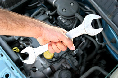 picture of hand holding a wrench over a car motor